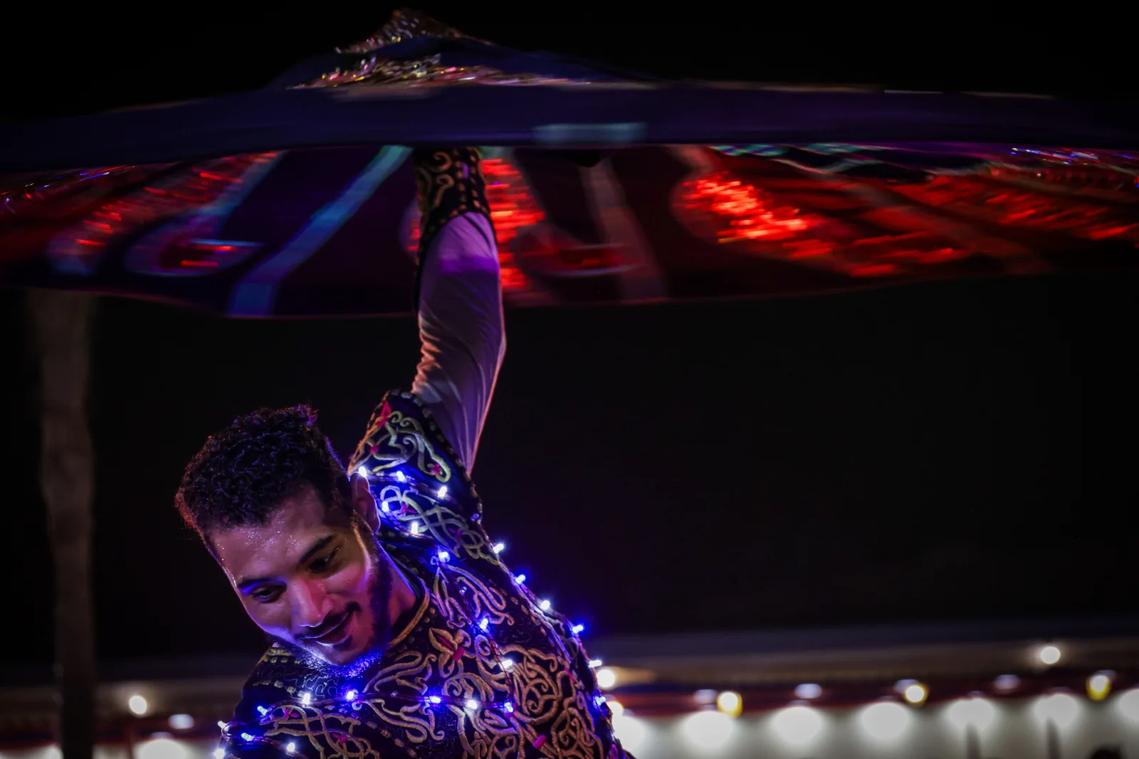 A Tanoura dancer spinning close-up under coloured stage lights at night (representative photograph, not Al Hadheerah's own stage)