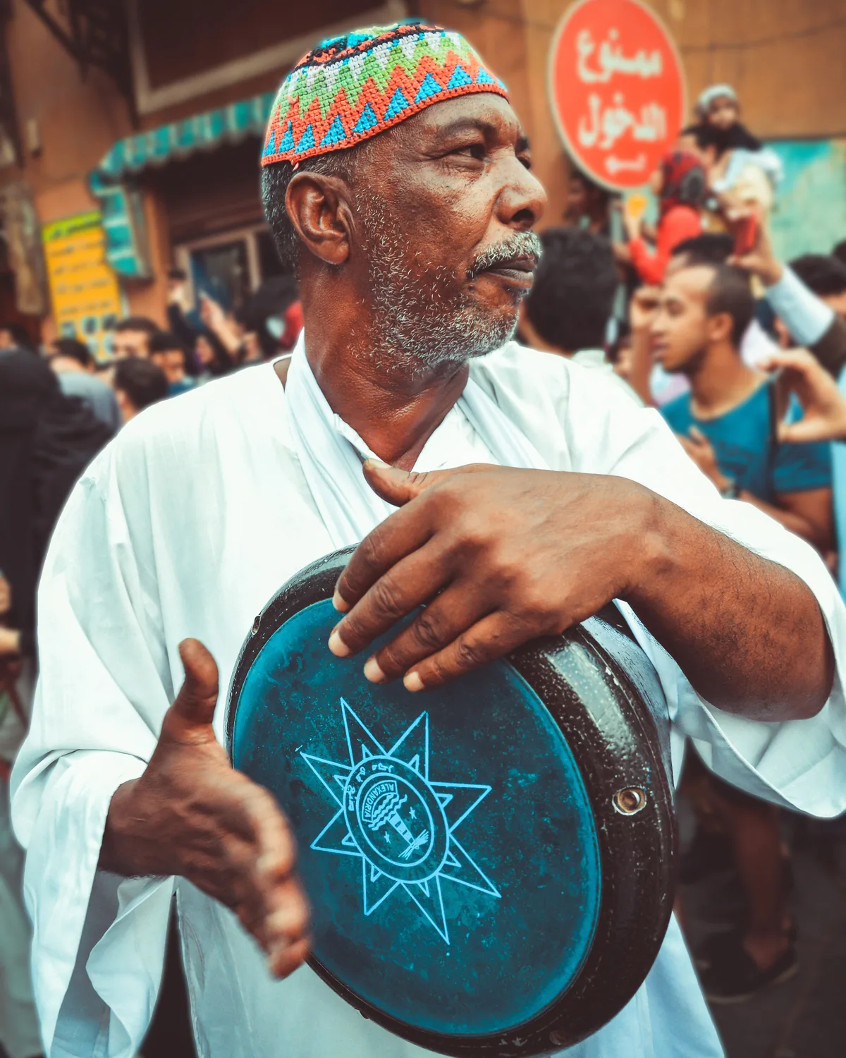 A musician in traditional dress playing a hand-held frame drum at a Middle Eastern street festival (representative photograph, not Al Hadheerah's own band)